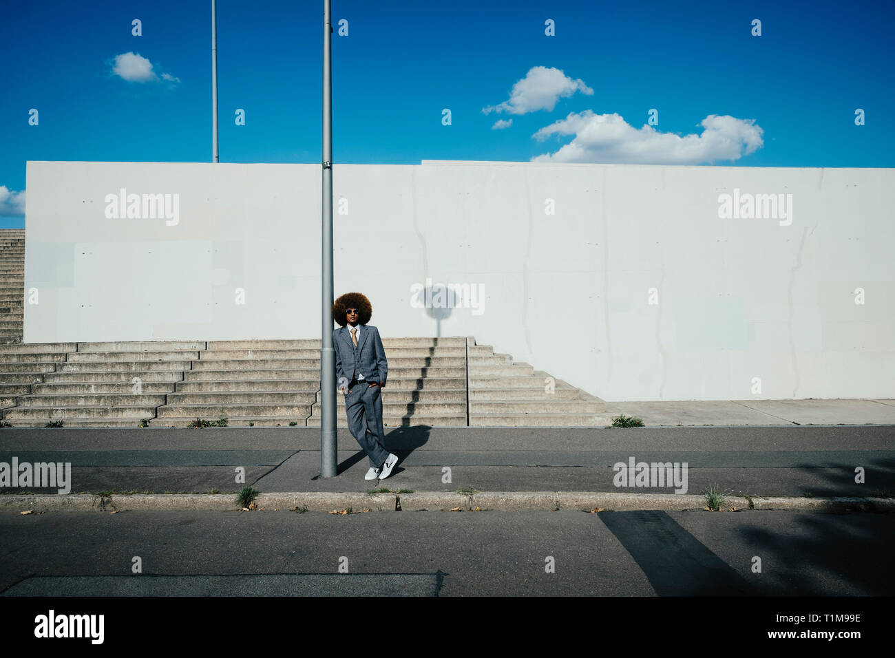 Ritratto fiduciosi, fresca e ben vestito giovane con afro sul marciapiede urbano Foto Stock