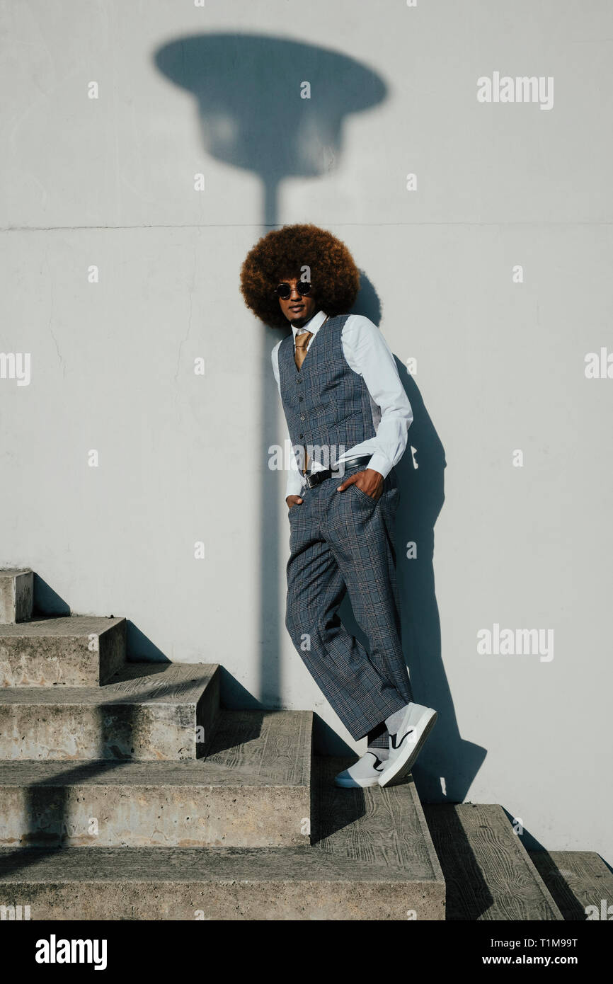 Ritratto fiduciosi, fresca e ben vestito giovane con afro su fasi urbane Foto Stock