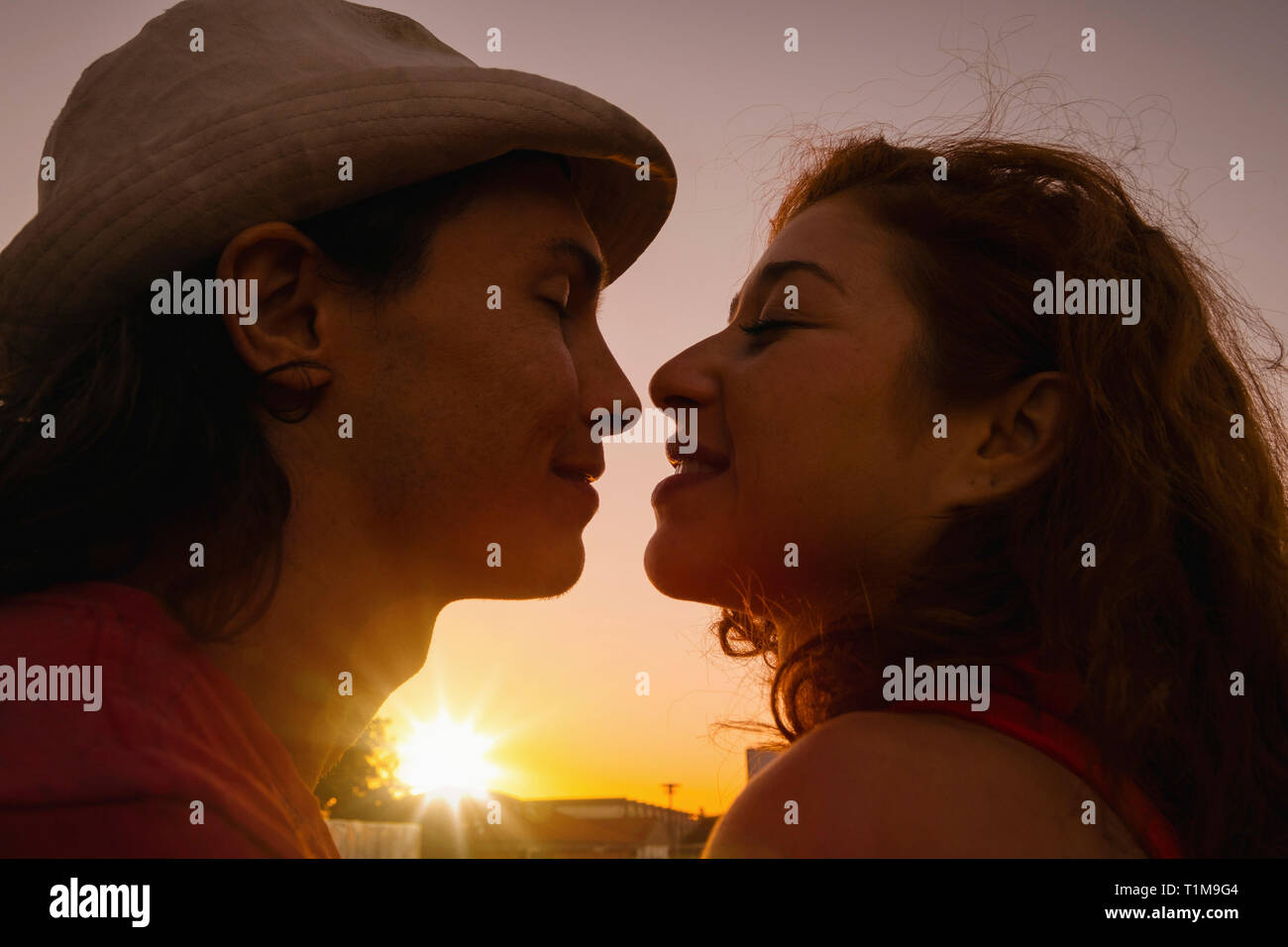 Coppia affettuoso bacio con il tramonto del sole in background Foto Stock
