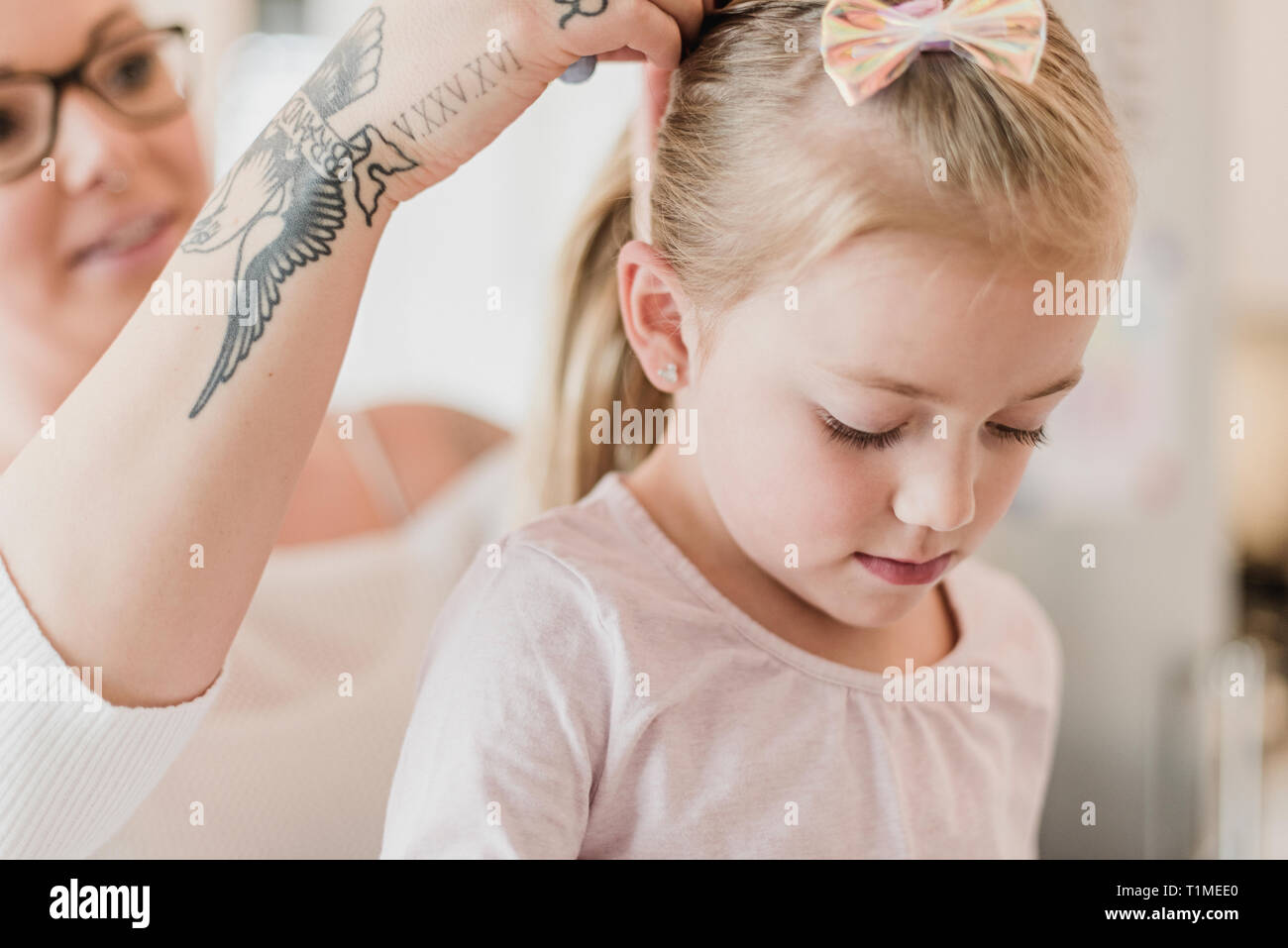 Madre con tatuaggi daughterÕs fissaggio capelli Foto Stock