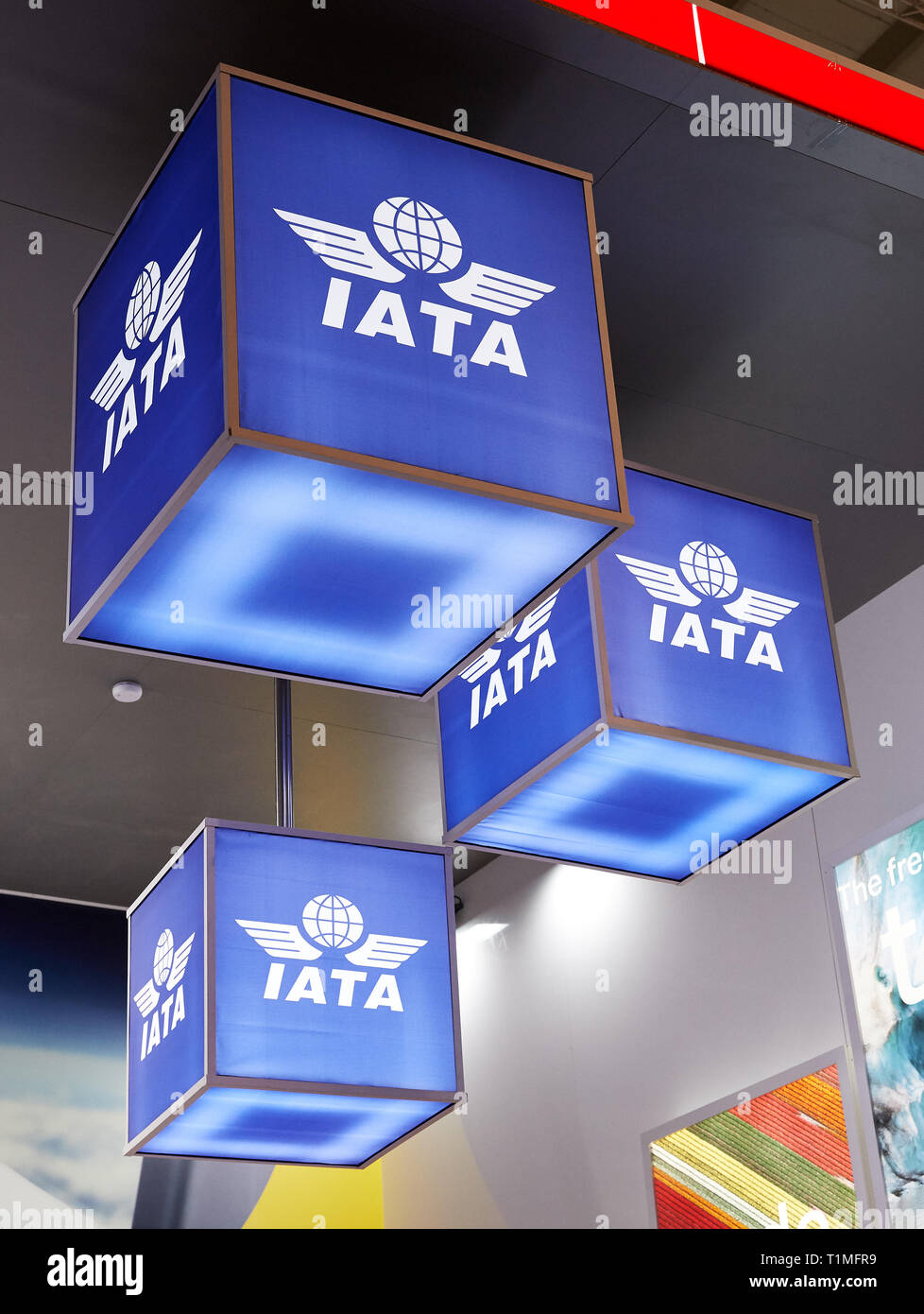 08.03.2019, Berlin, Berlin, Germania - IATA stand alla fiera ITB. Illuminato blu a cubetti con il logo dell'associazione appesi al soffitto o Foto Stock