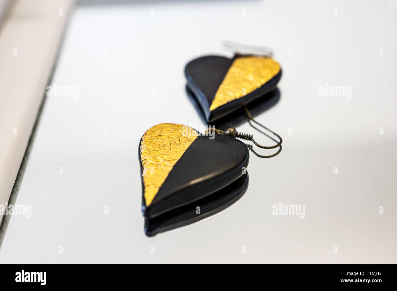 Close-up di manufatti in fimo orecchini ispirati dall amore, forme delicate e l eterna combinazione di nero e oro. Profondità di messa a fuoco. Foto Stock