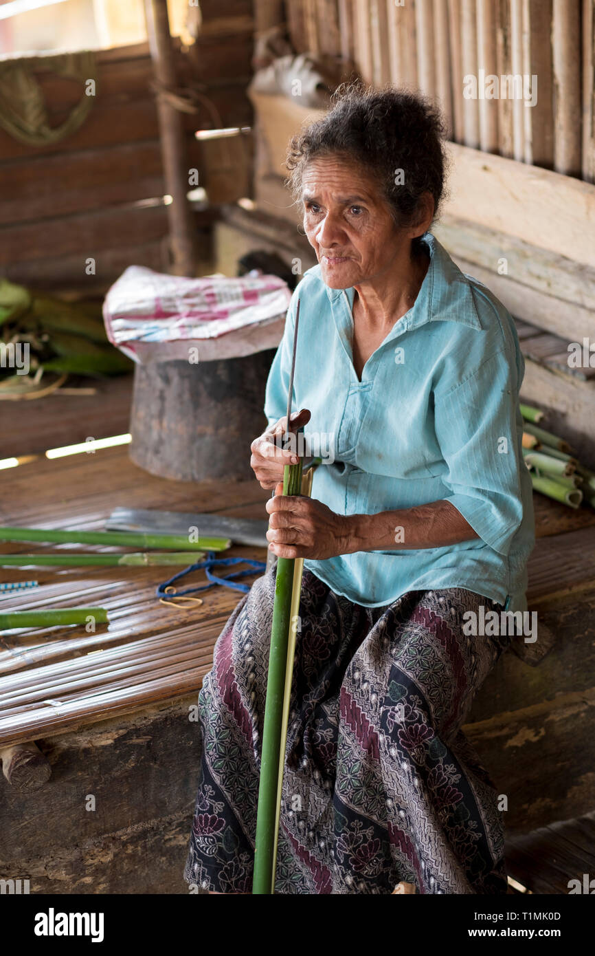 Alfur indigeni persone del gruppo Nuaulu cuciture di foglie di palma, isola Seram, Molucche, Indonesia Foto Stock
