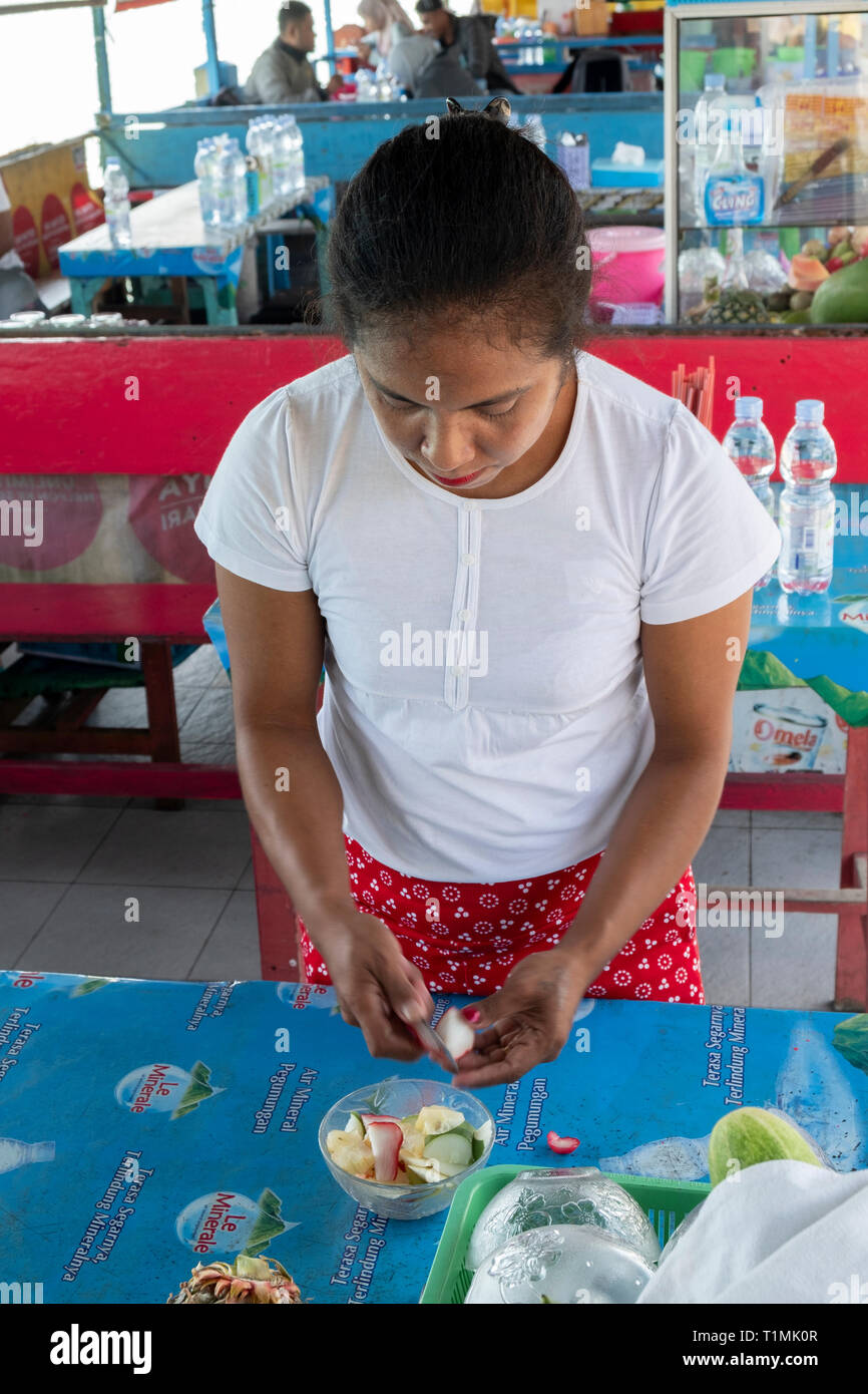 Una donna indigena da Seram preparare una speziata insalata di frutta, Molucche, Indonesia Foto Stock