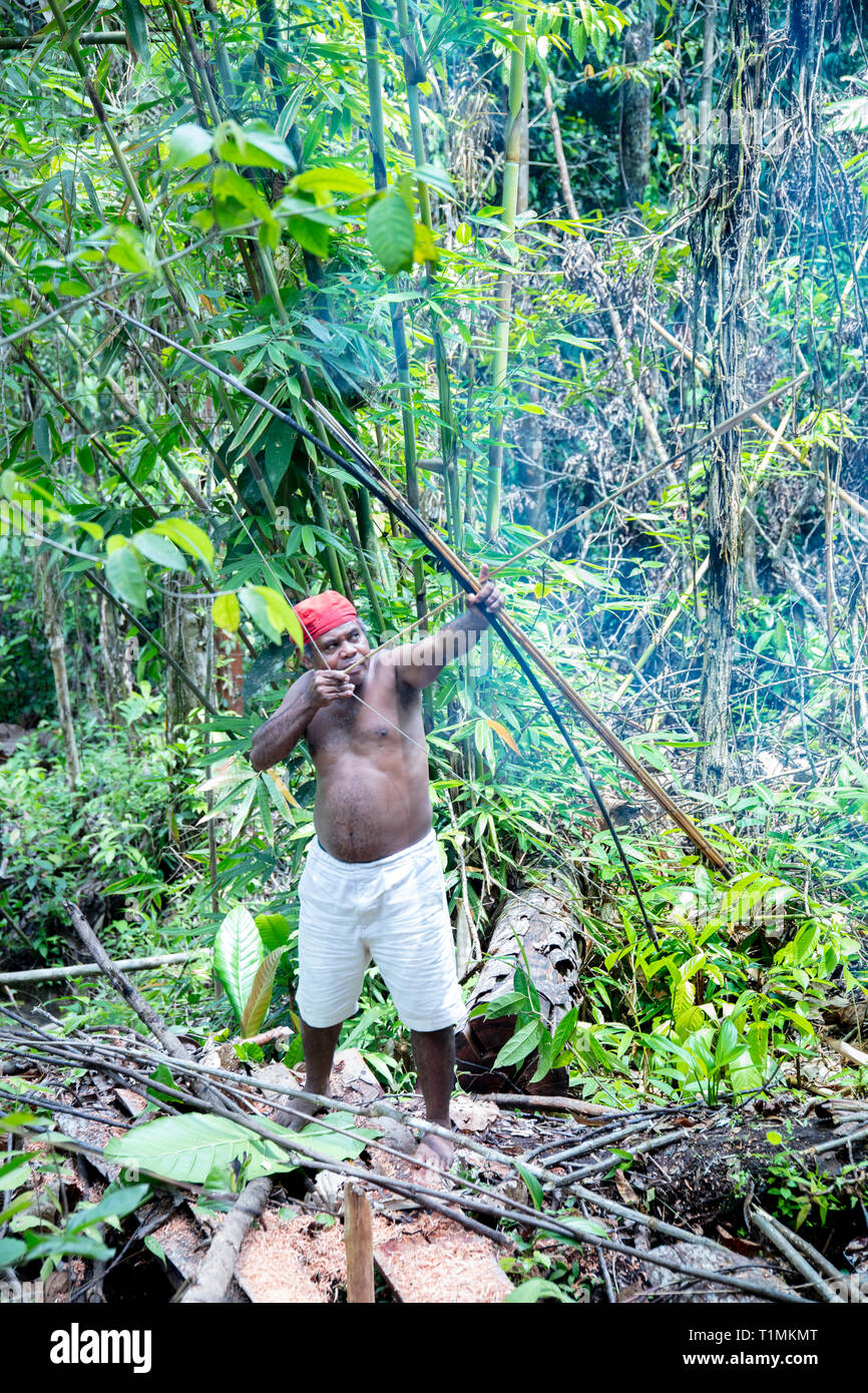 Alfur indigeni cacciatore del gruppo Nuaulu con arco e frecce nella foresta pluviale, isola Seram, Molucche, Indonesia Foto Stock
