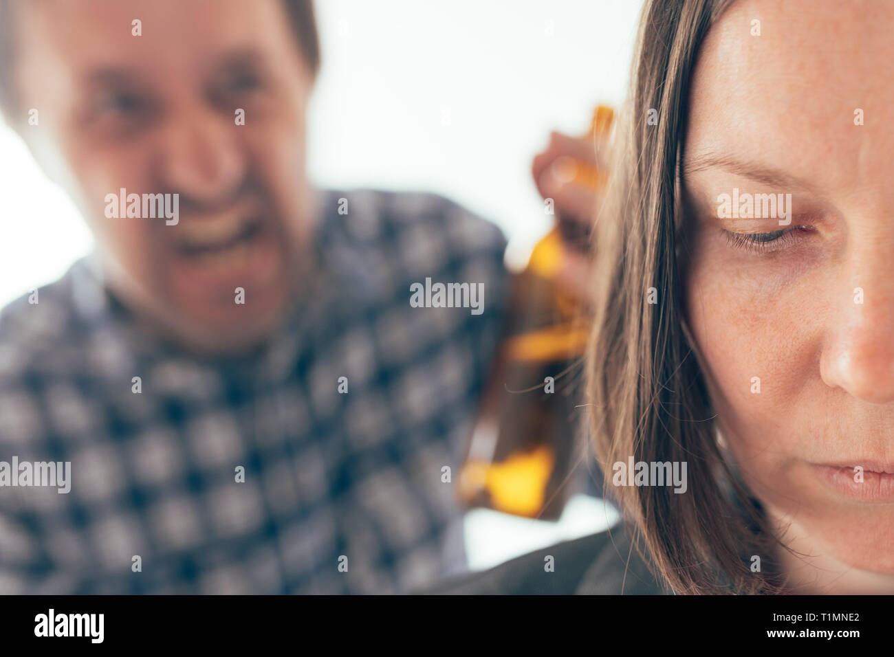 Uomo ubriaco bere birra e sostenendo con la moglie a casa, caucasico adulto giovane nella controversia interna concept a urlare contro l'altra. Foto Stock