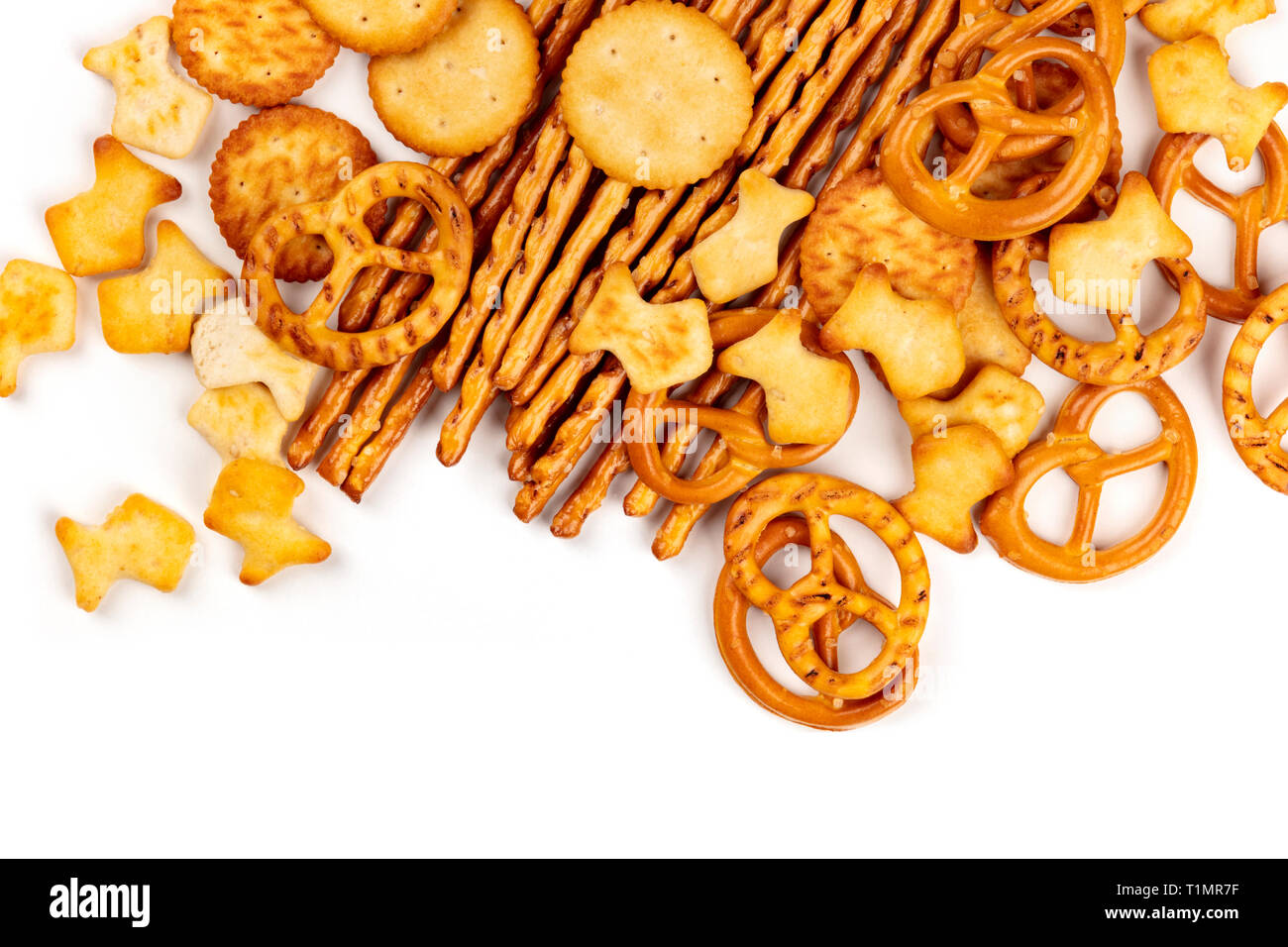 Molti cracker salato, bastoncini, salatini e pesci dorati, girato dalla parte superiore su uno sfondo bianco con copia spazio. Party Mix snack banner Foto Stock