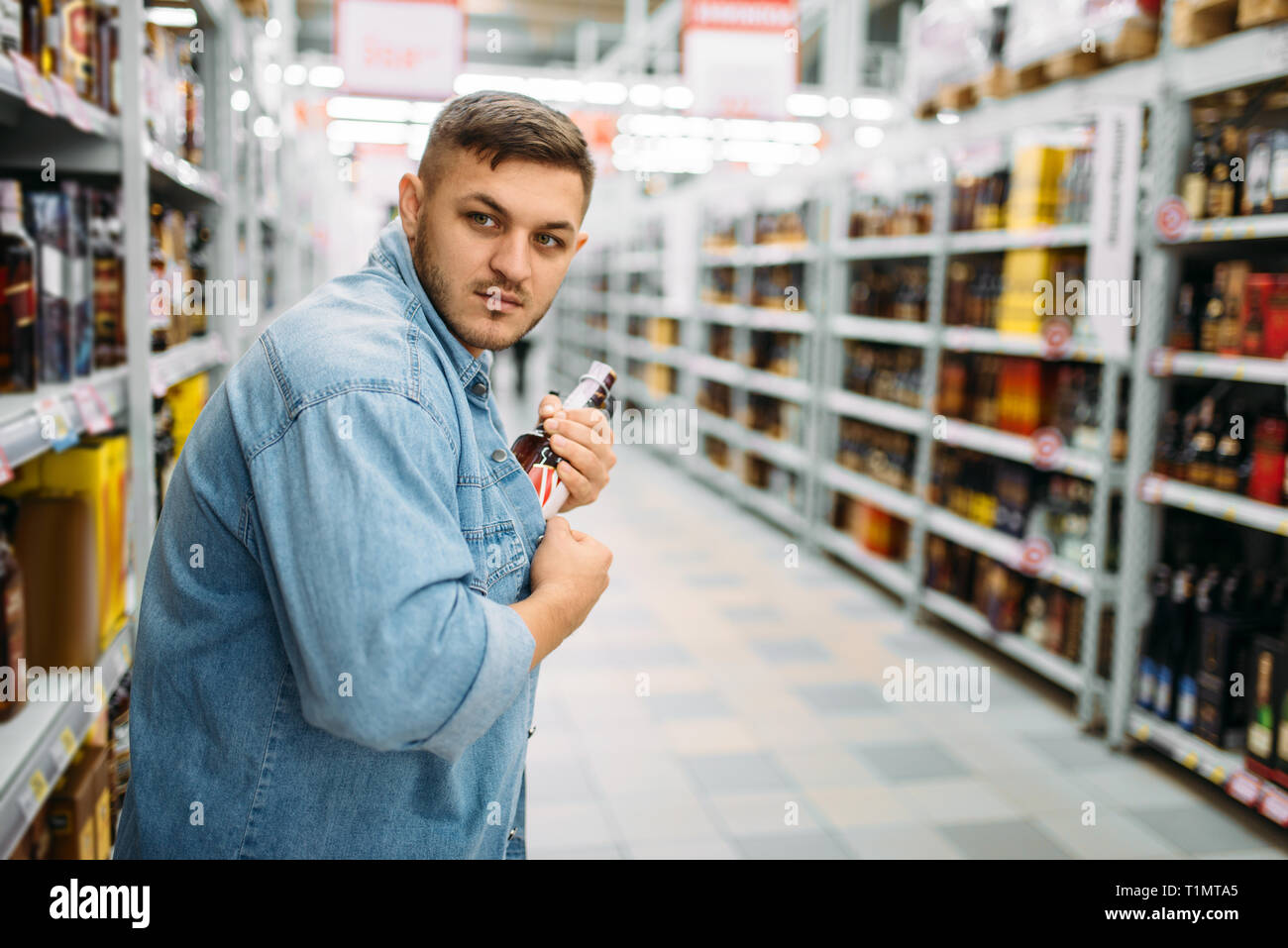 L uomo si nasconde una bottiglia di alcool sotto la sua maglietta Foto Stock