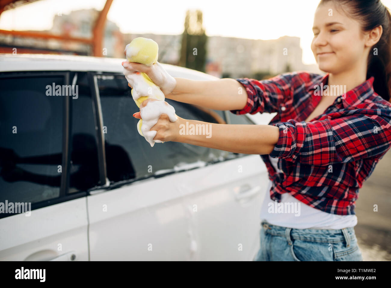 Persona di sesso femminile il lavaggio di finestra del veicolo con schiuma Foto Stock