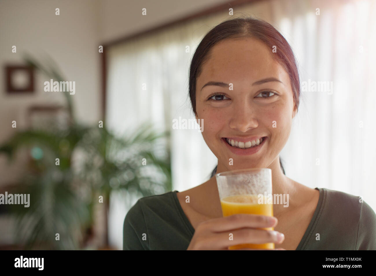 Ritratto fiducioso giovane donna di bere succo di arancia Foto Stock