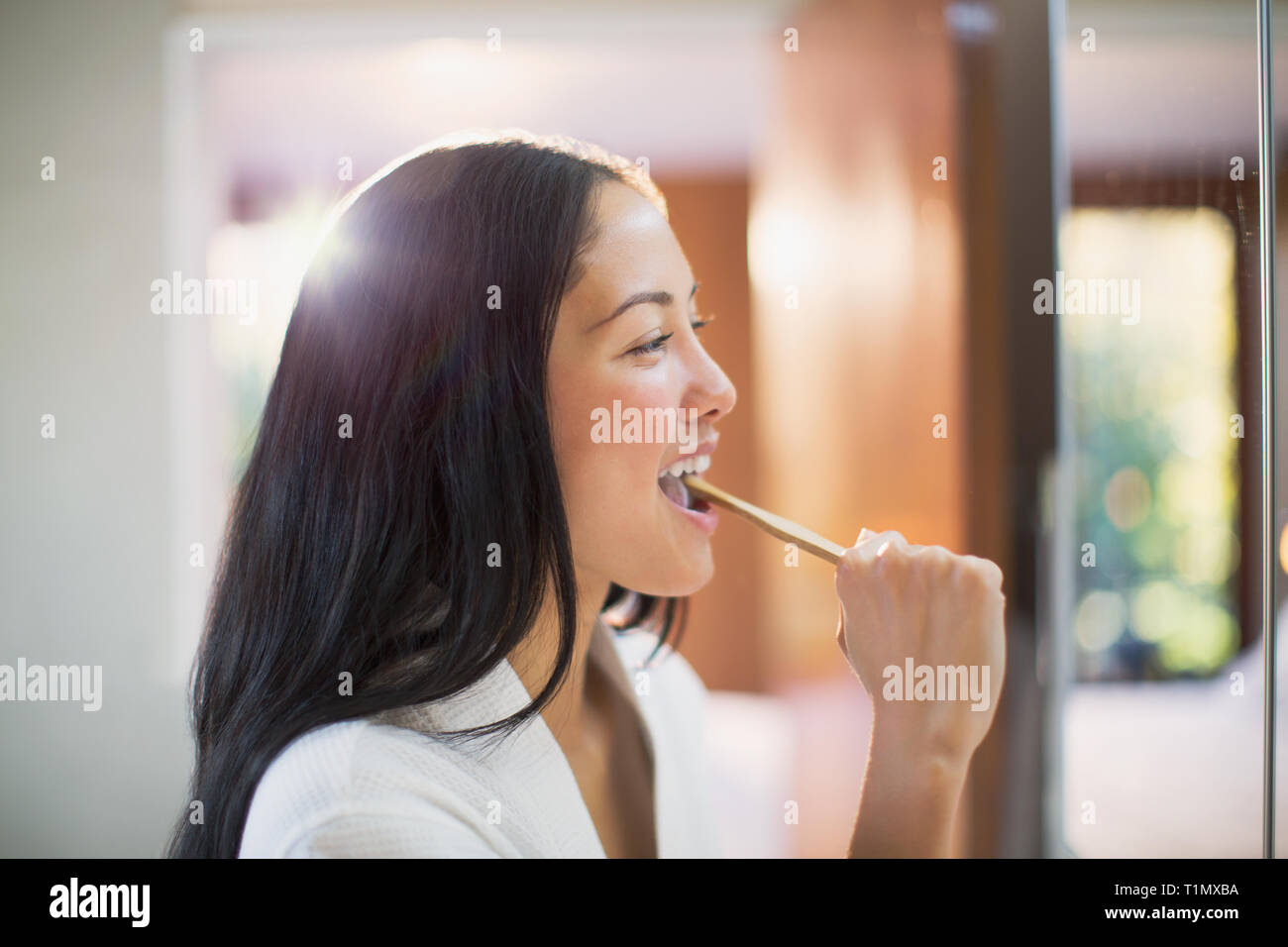 Giovane donna spazzolare i denti in Specchio bagno Foto Stock