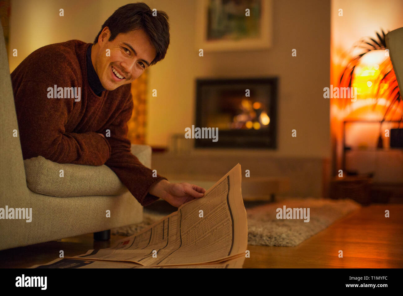 Ritratto uomo sorridente leggendo il giornale in soggiorno Foto Stock