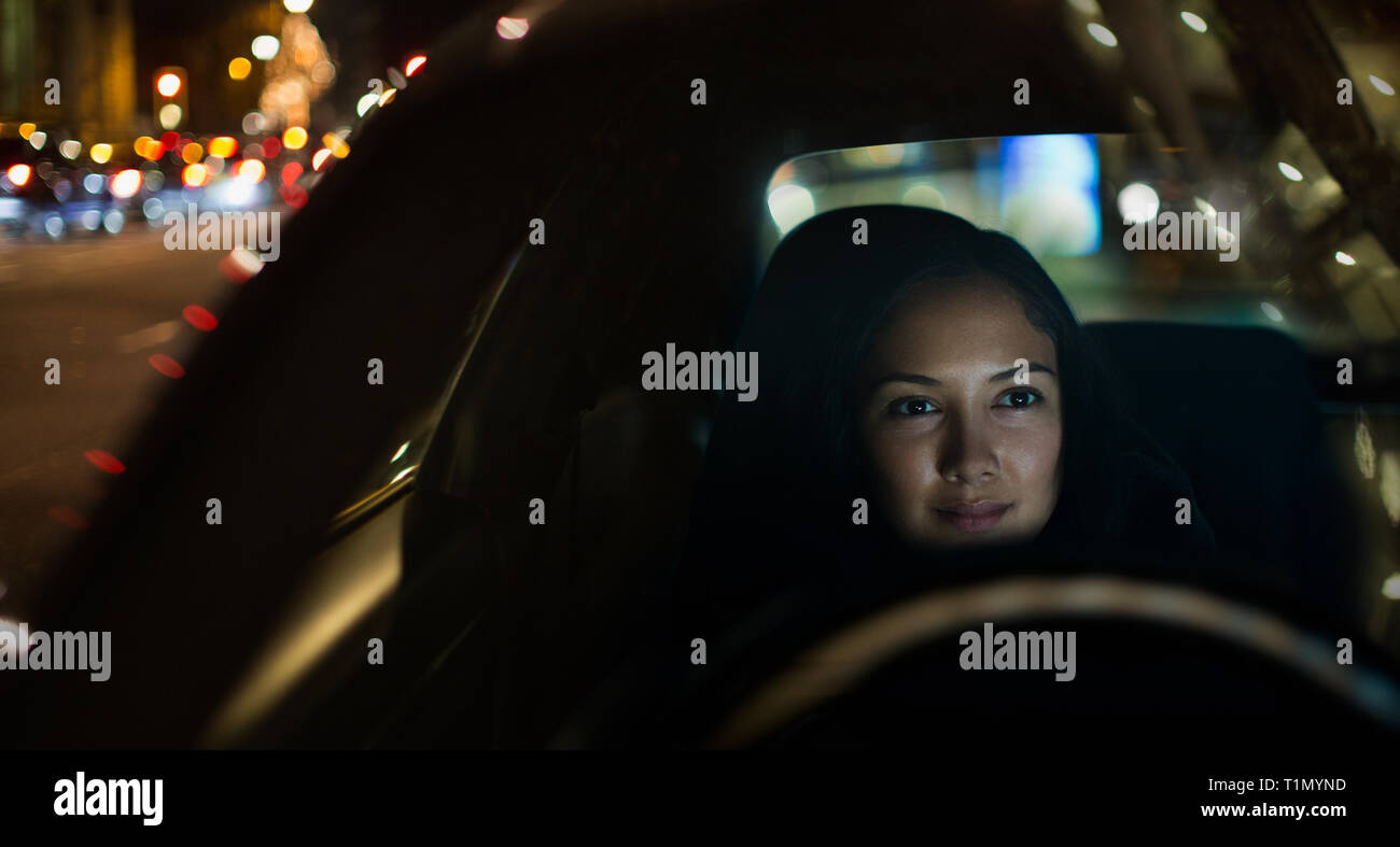 Giovane donna alla guida di auto di notte Foto Stock