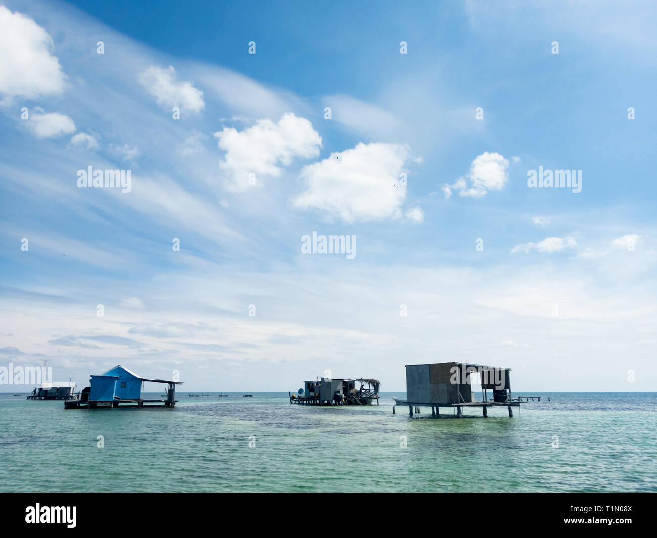 Capanne per la pesca a palafitte costruite sopra la baia e la barriera corallina poco profonde Foto Stock