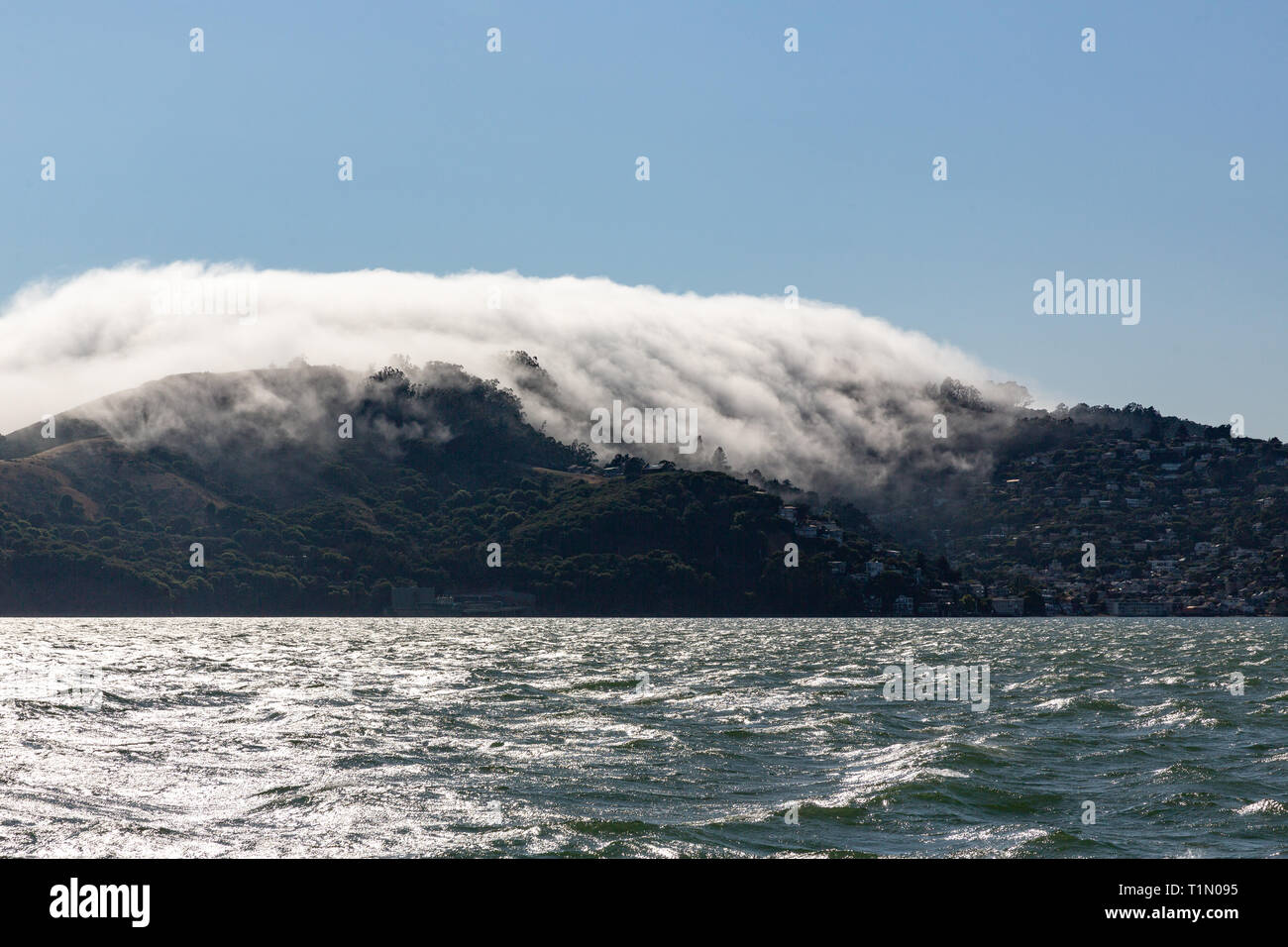 Nuvole basse scendono su montagne in Sausalito, California avvicinando l'acqua in una giornata di sole Foto Stock