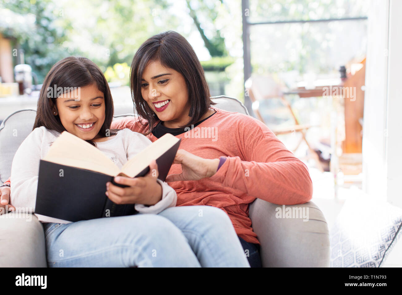 Madre e figlia libro lettura in poltrona Foto Stock