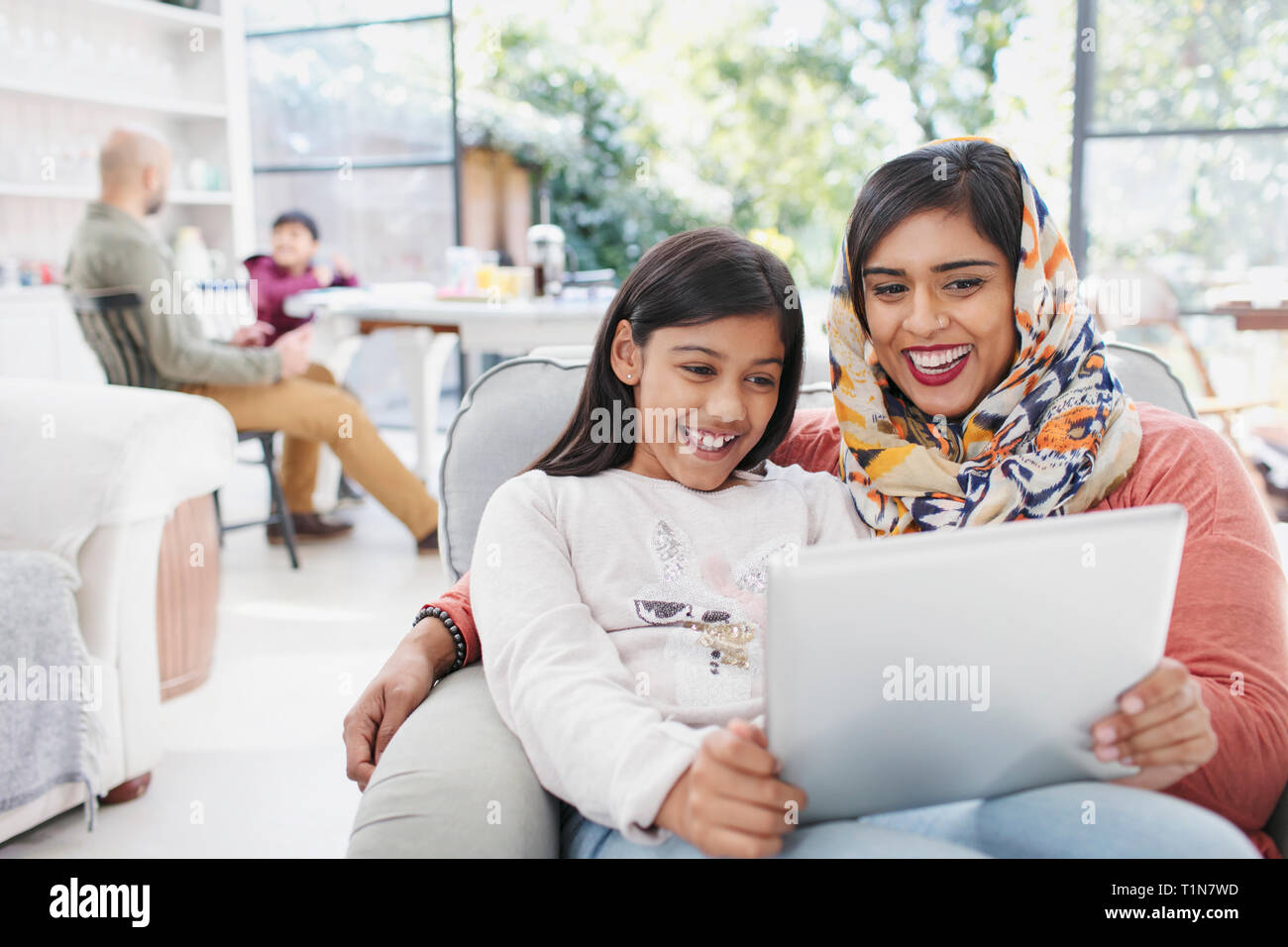 Felice madre in hijab e figlia utilizzando tavoletta digitale Foto Stock