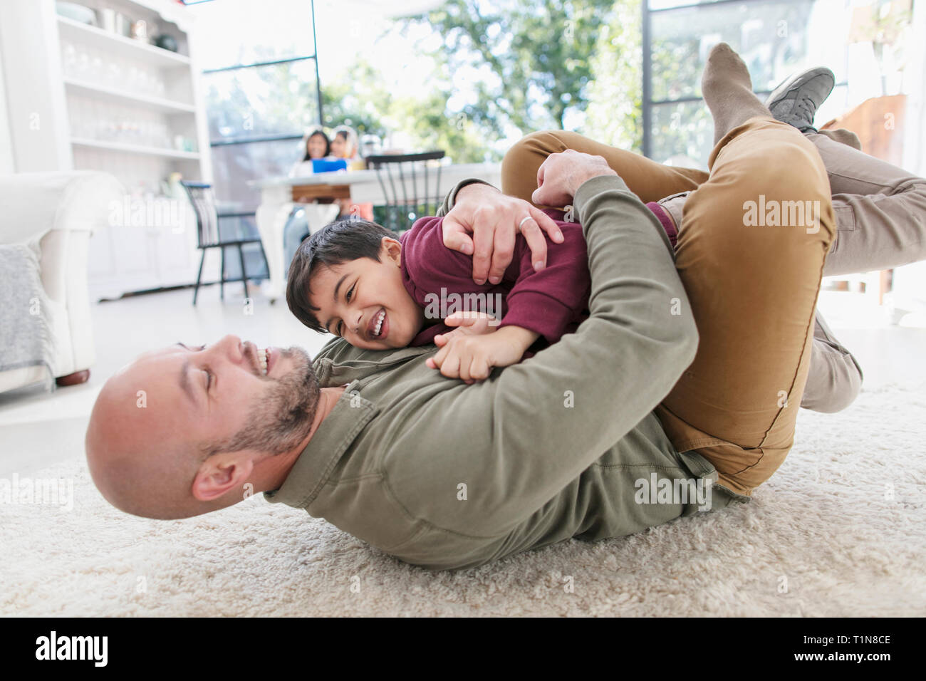 Giocoso padre e figlio abbracciando sul pavimento Foto Stock