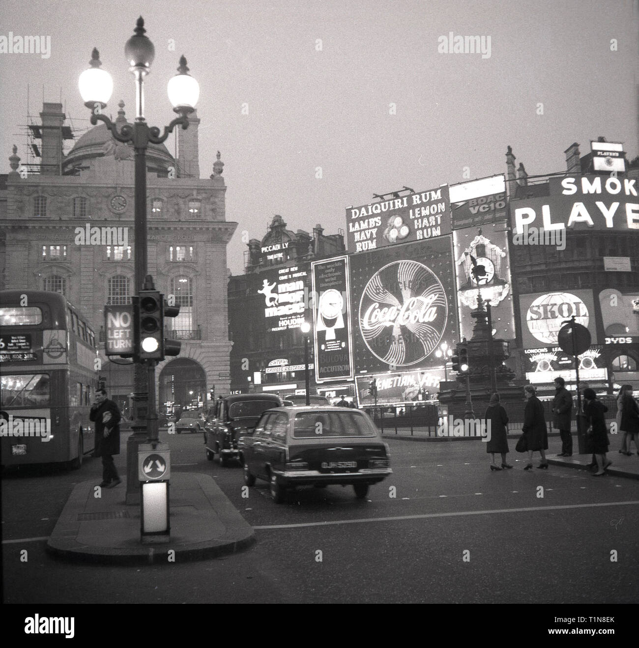 Anni '1960, Londra, Piccadilly Circus, che mostra il trasporto del tempo e le luci al neon dei cartelloni pubblicitari, con i marchi dell'epoca come Skol lager e Players Cigarettes, West End, Lonon, Inghilterra, Regno Unito. Foto Stock