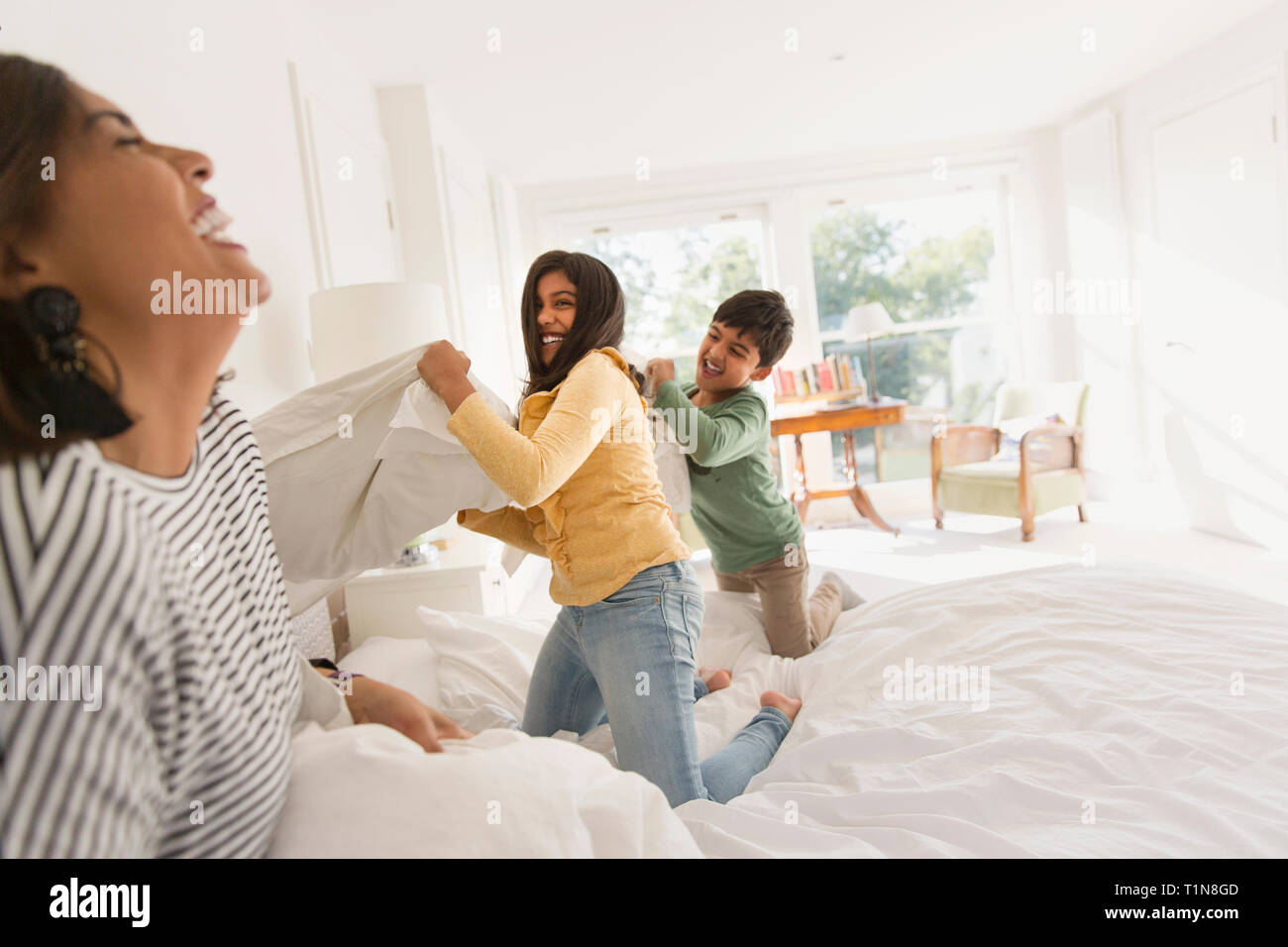 Giocoso madre e figli godendo lotta di cuscini sul letto Foto Stock