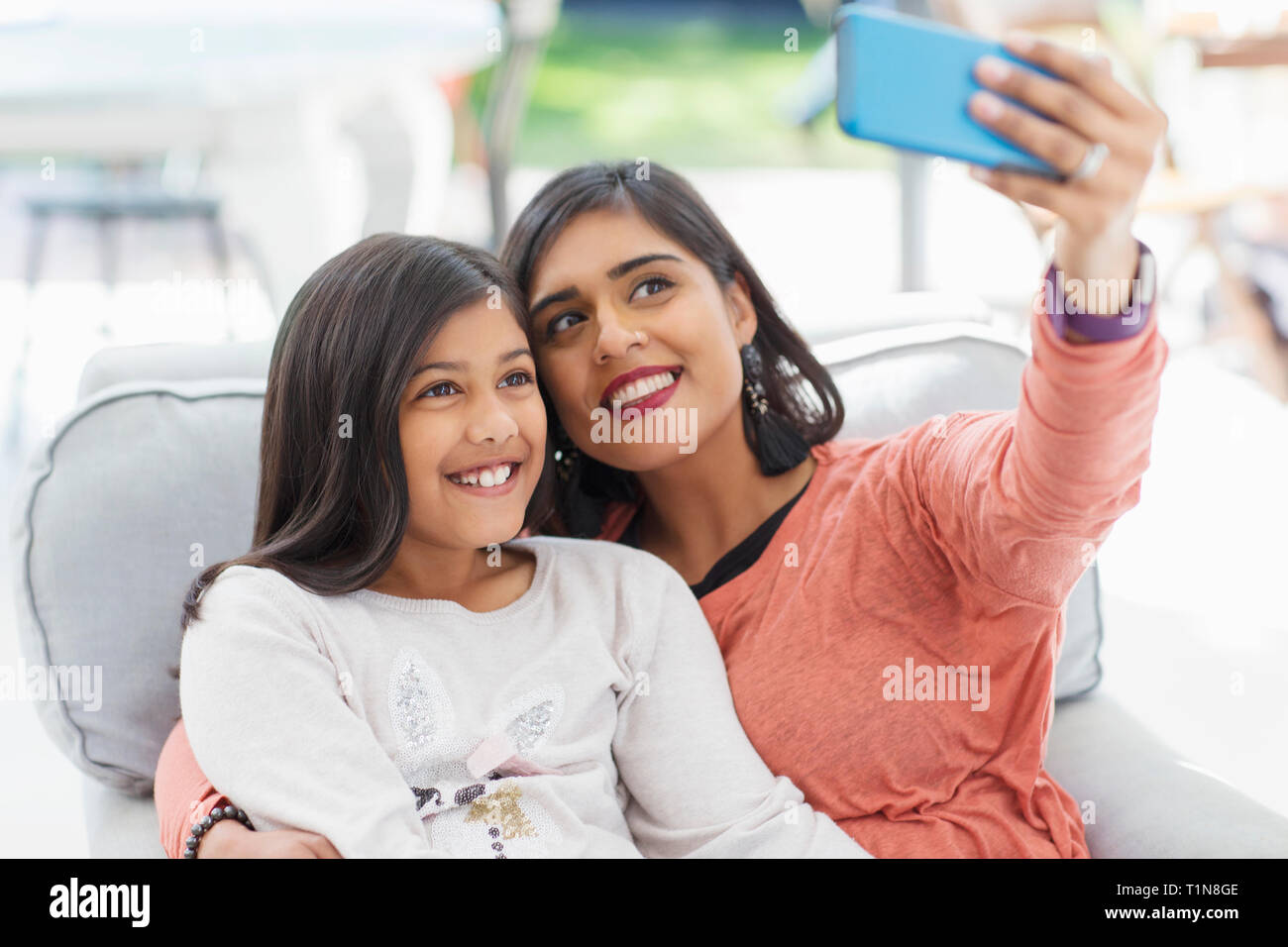 Felice madre e figlia tenendo selfie con smart phone in poltrona Foto Stock
