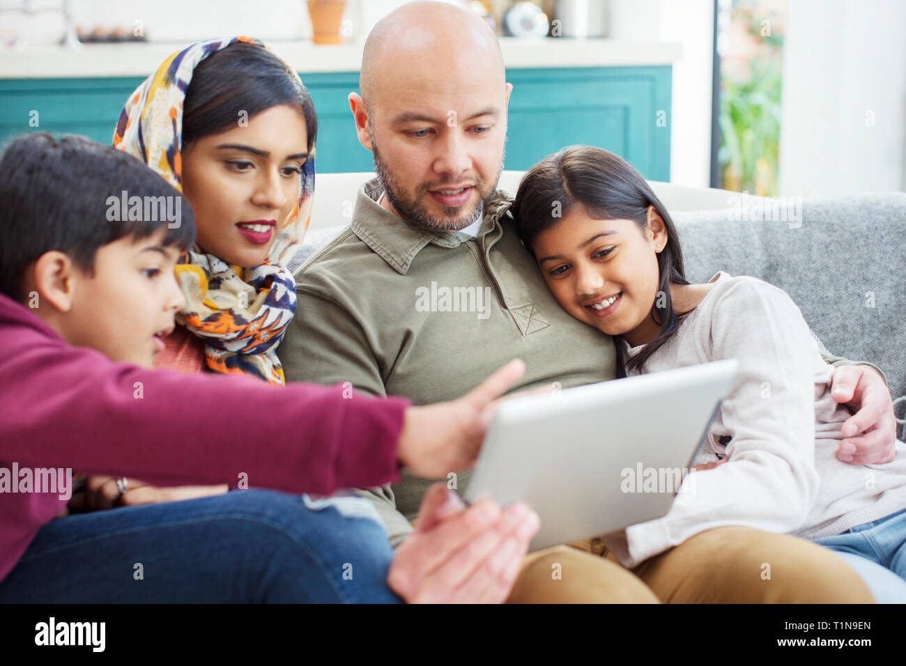 La famiglia tramite tavoletta digitale sul divano Foto Stock