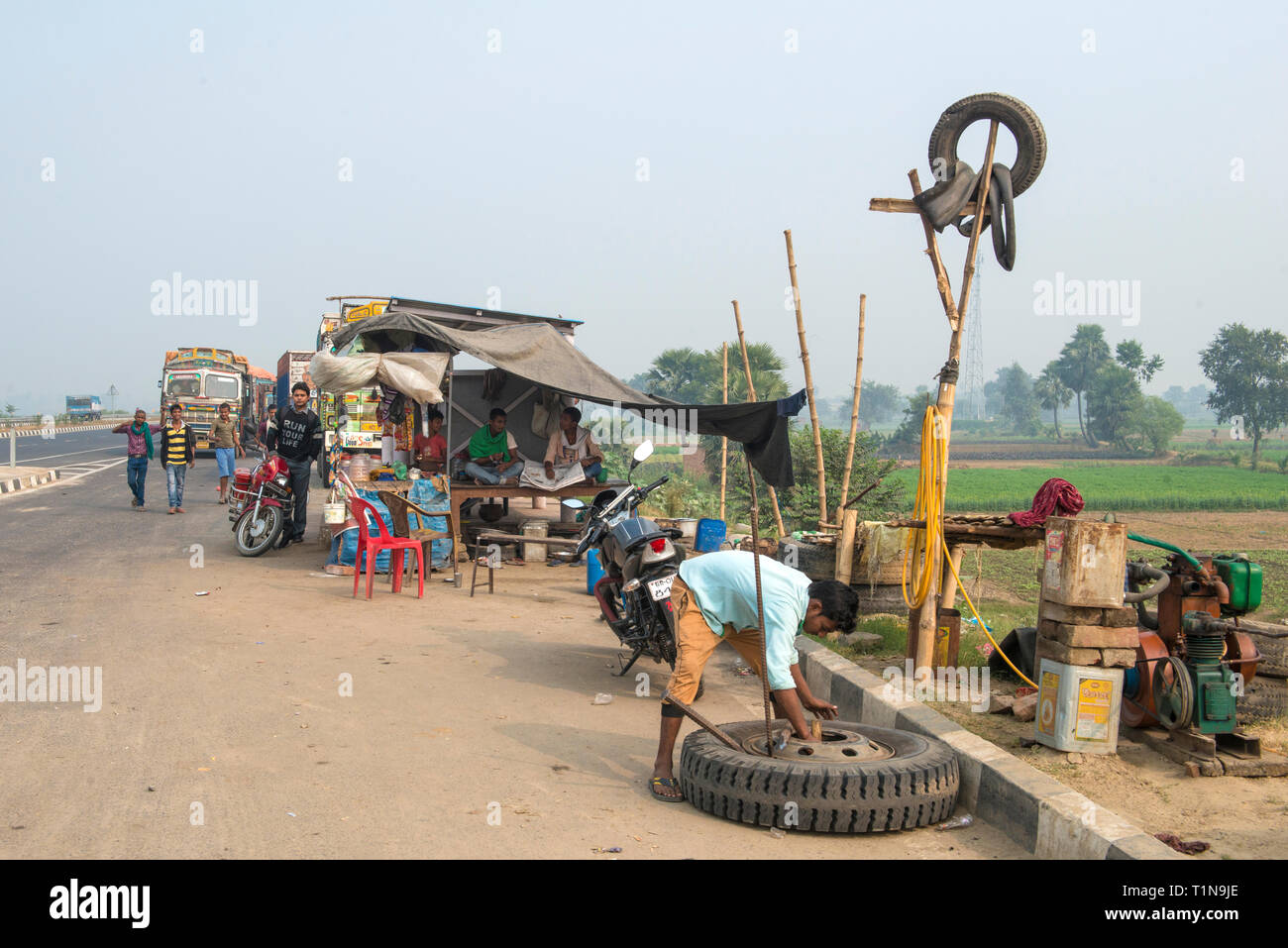 INDIA, BIHAR uomo che ripara un carrello pneumatico di fronte a un piccolo pneumatico Negozio riparazione lungo una strada principale nei pressi di Allahabad Foto Stock