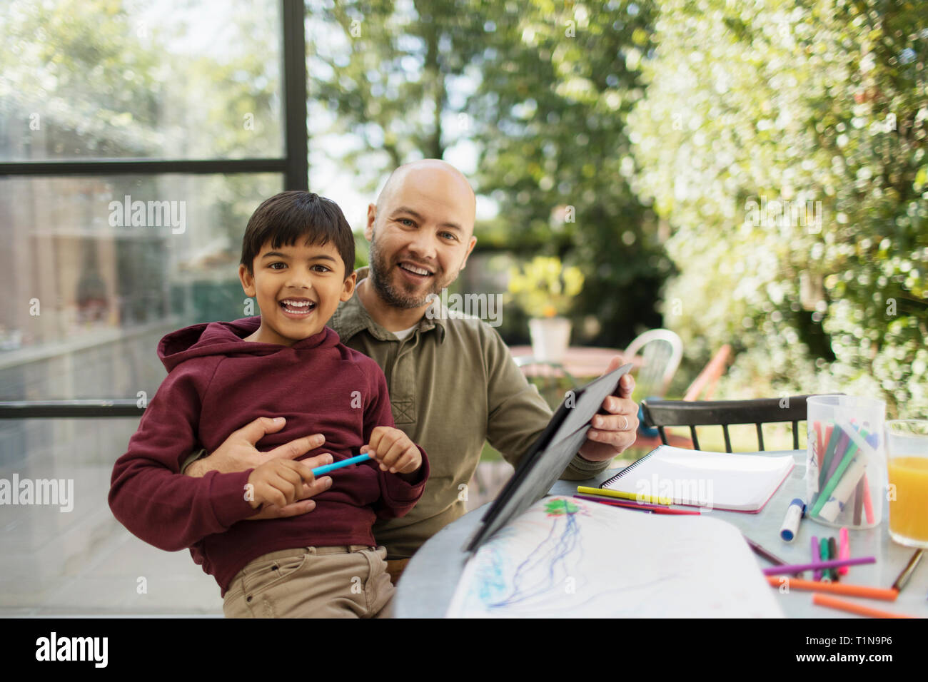 Ritratto felice il Padre e il figlio e di colorazione con tavoletta digitale a tavola Foto Stock