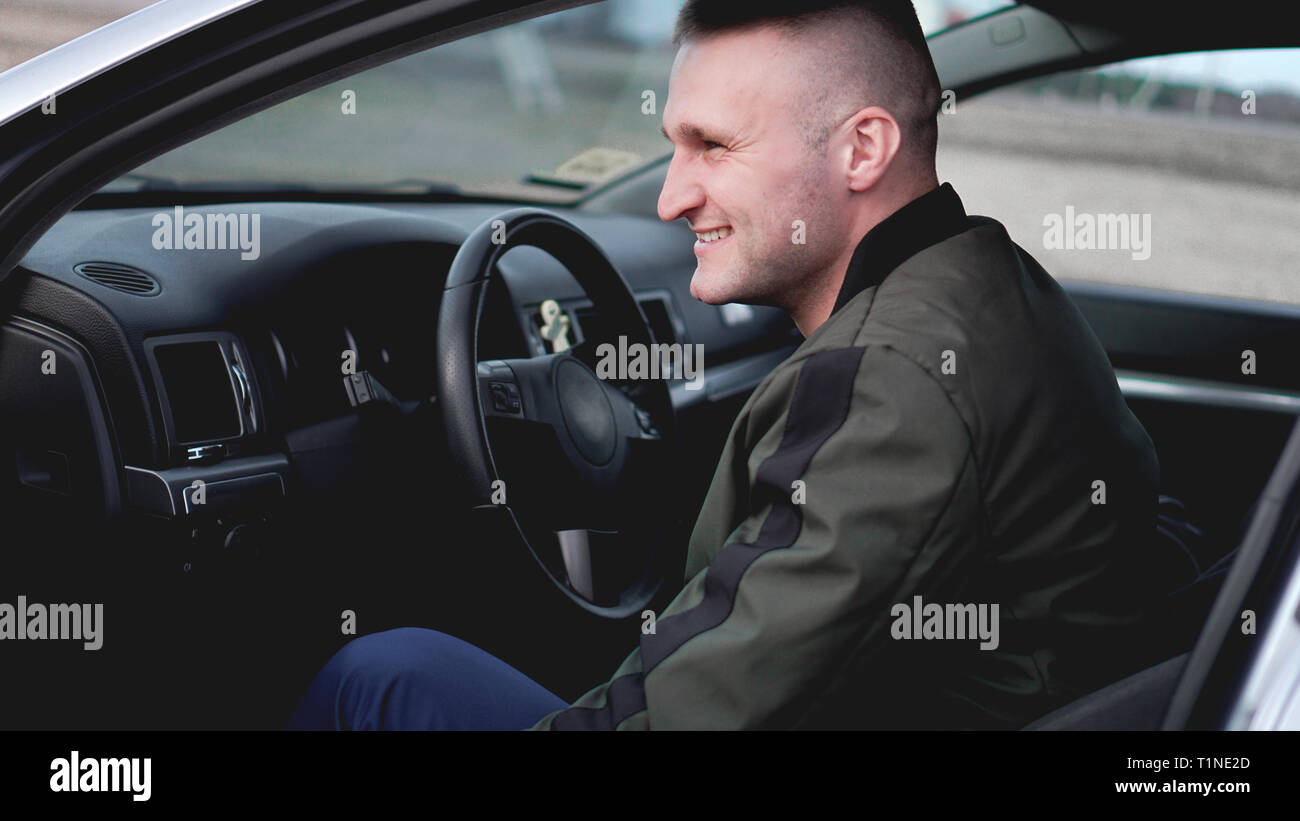 Attraente sorridendo felice giovane uomo in auto Foto Stock