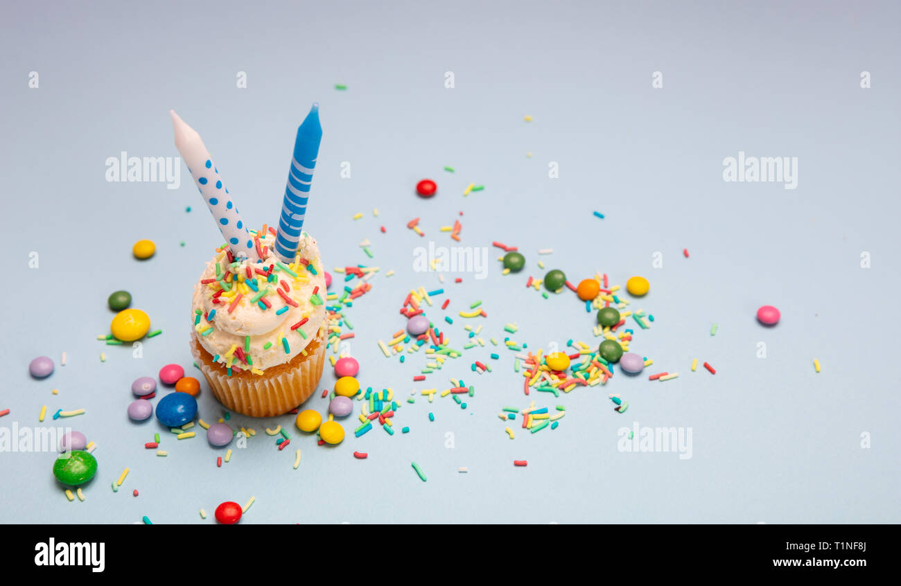 Ragazzo compleanno. Tortina vaniglia con due candele blu su sfondo color pastello, copia dello spazio. Foto Stock