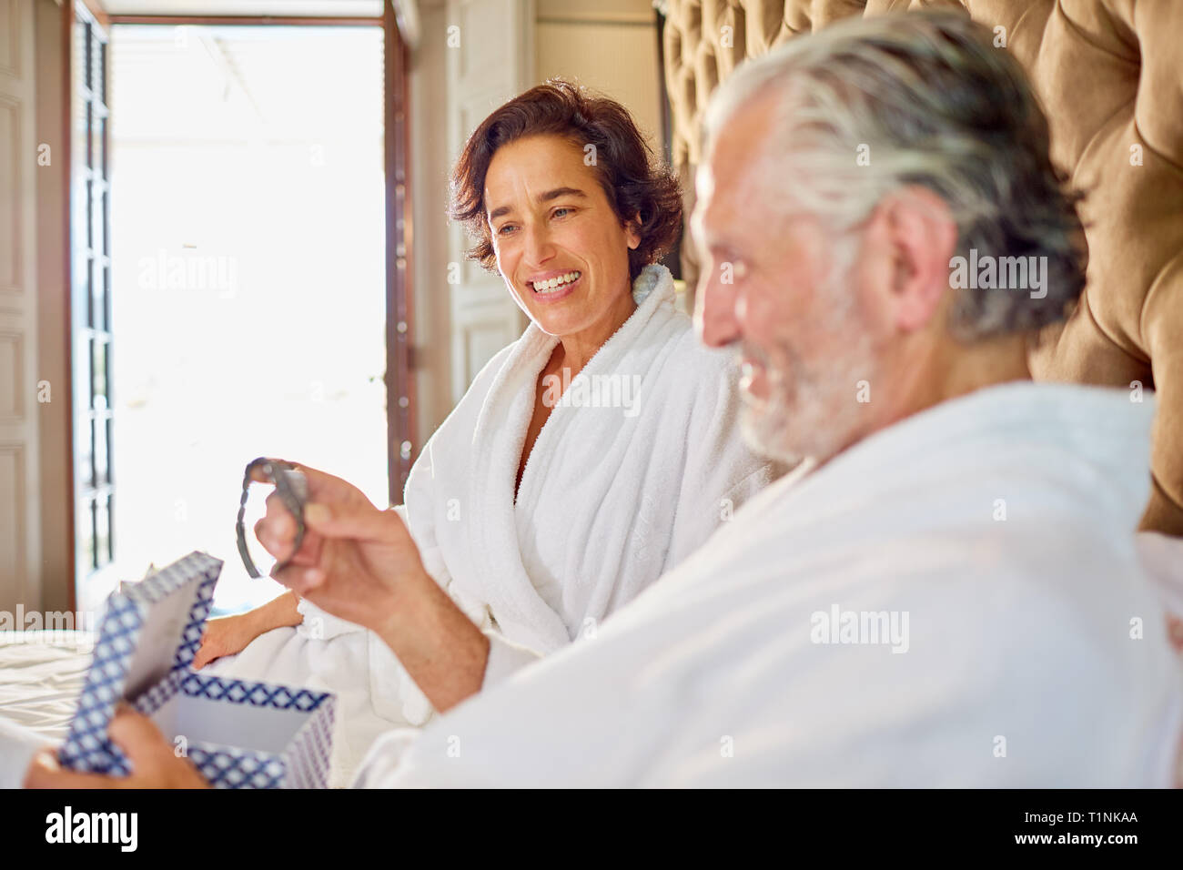 Moglie dando un orologio da polso al marito sul letto di hotel Foto Stock