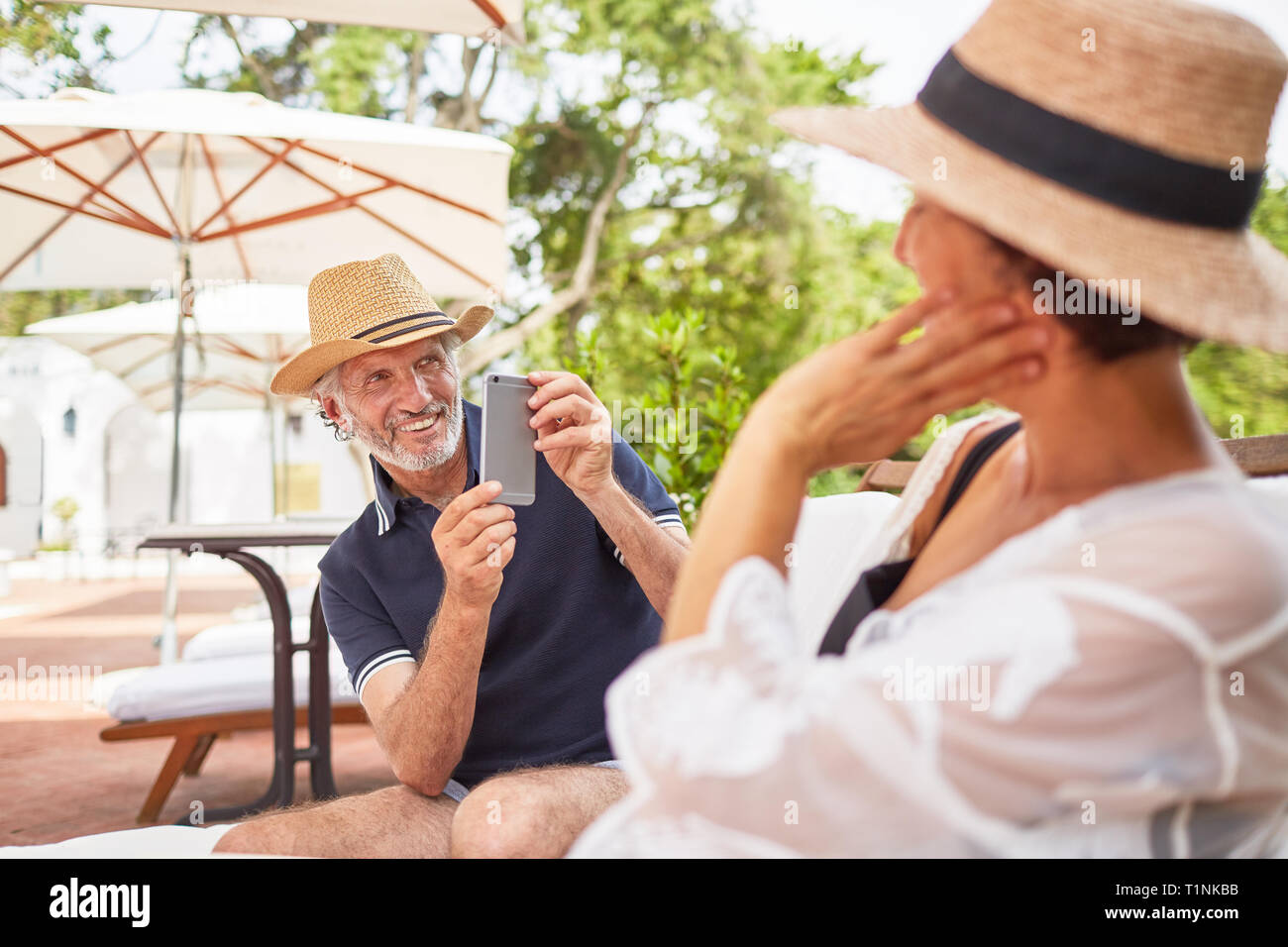 Il marito con la fotocamera del telefono fotografare la moglie a bordo piscina Foto Stock