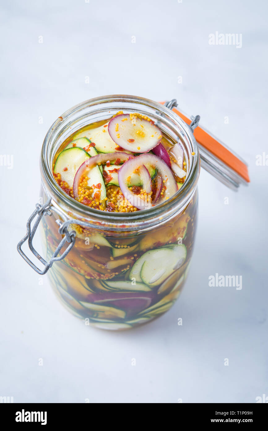 Vista superiore del vegetale piccante pickle antipasto in un aperto mason jar e uno sfondo bianco. Decapare le zucchine e le cipolle rosse in una marinata piccante. Foto Stock