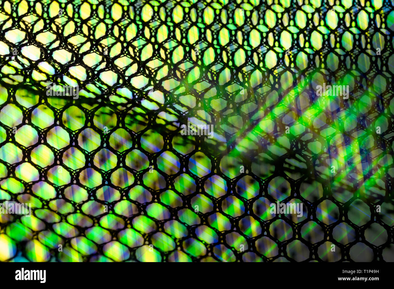 Netting ondulate. I raggi di luce dettaglio artistico. Abstract tessitura a maglia. Verde brillante lightbeams attraverso il nero celle esagonali. Shiny grid pattern sfondo. Foto Stock
