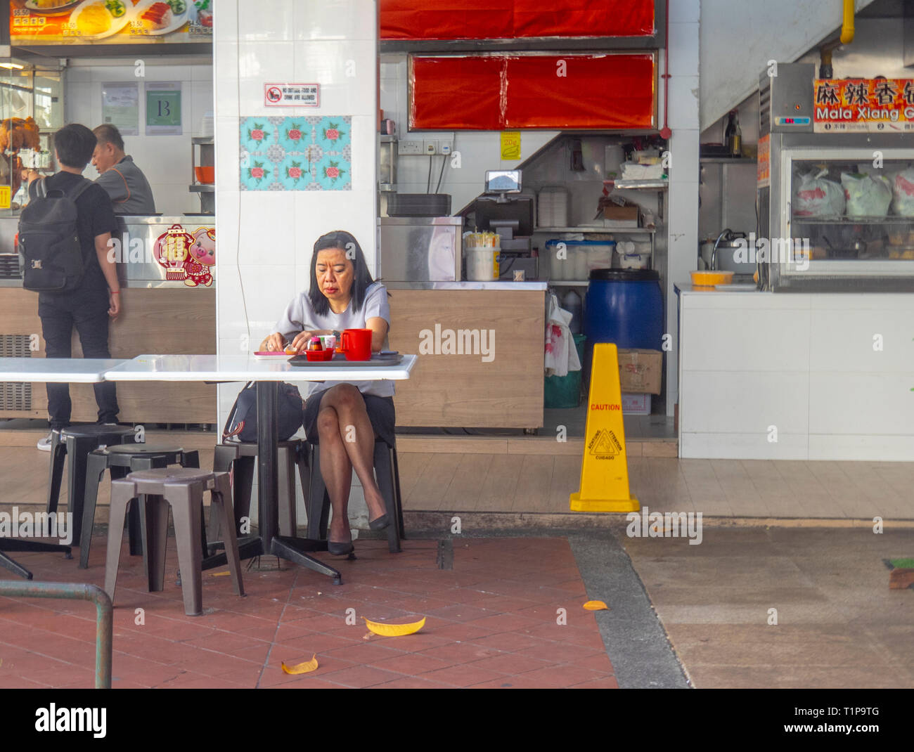 Donna asiatica seduti a mangiare la colazione al fresco presso un ristorante a Singapore Foto Stock