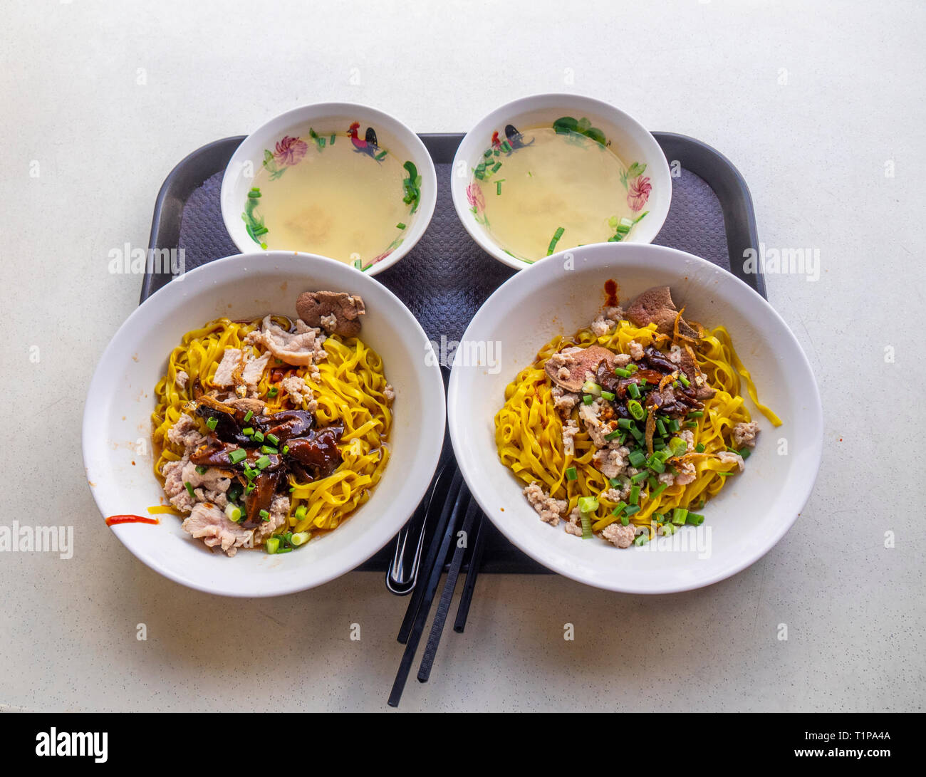 Il vassoio con la tradizionale colazione di Singapore due ciotole di di Tagliatelle con funghi e carne macinata di maiale e 2 piccole ciotole di brodo. Singapore. Foto Stock