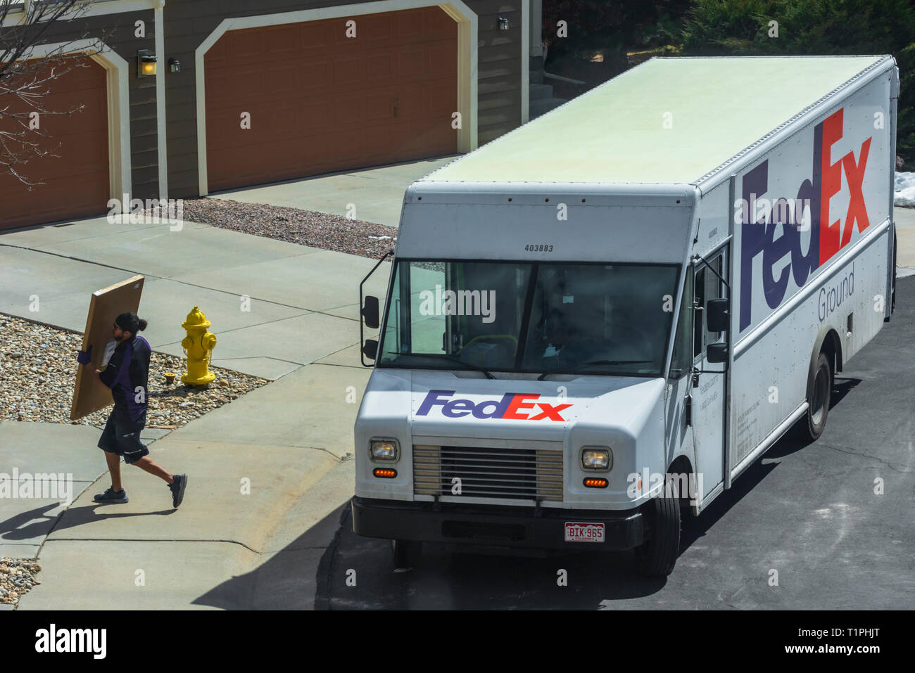 Federal Express delivery truck driver e pacchetto porta a casa residenziale, Castle Rock Colorado US. Foto scattata a marzo. Foto Stock