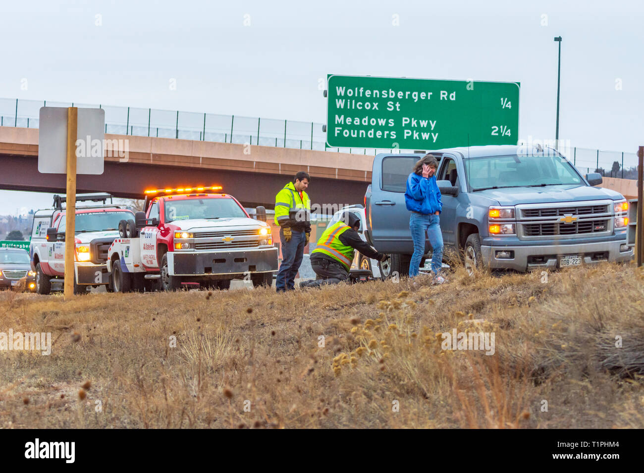 Donna automobilista ricevere assistenza per il pneumatico sgonfio lungo la Interstate 25 in serata, Castle Rock Colorado US. Foto scattata a marzo. Foto Stock