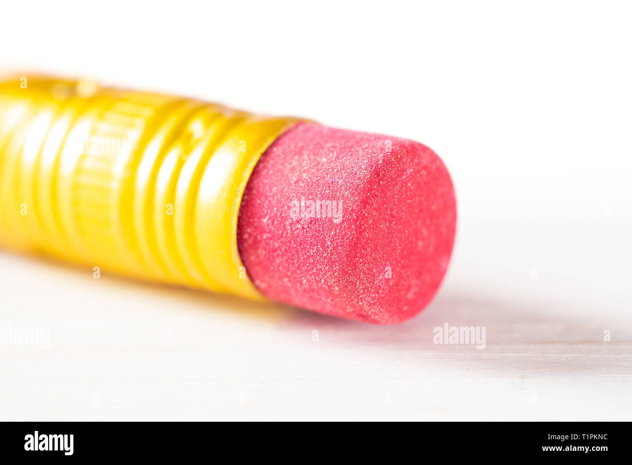 Primo piano di un pezzo di matita gialla cup eraser su legno bianco Foto Stock