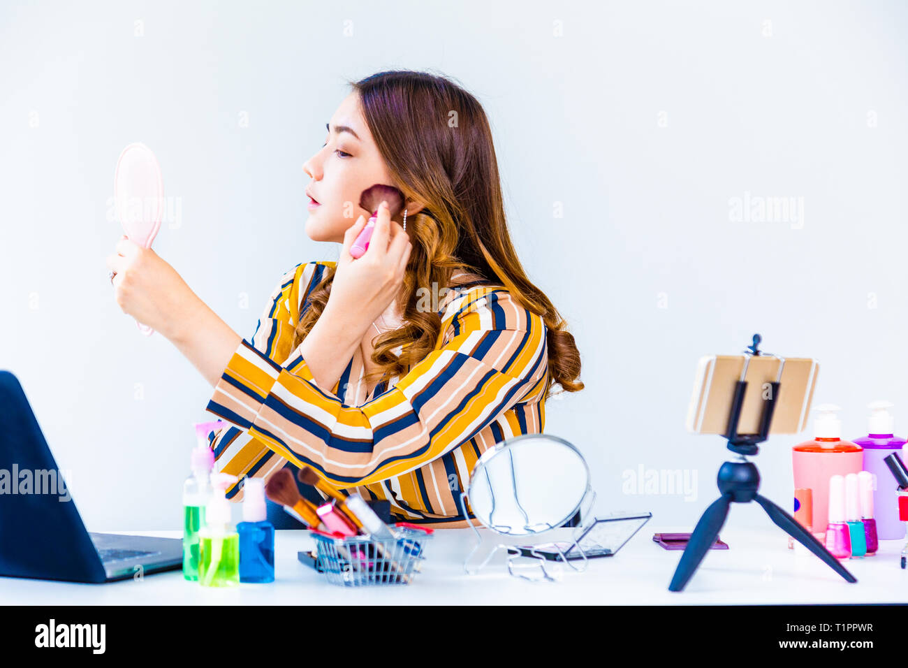 Bella giovane donna asiatica, vlogger, rivedendo i prodotti di bellezza che mostra come mettere compongono, per un blog di video a casa Foto Stock