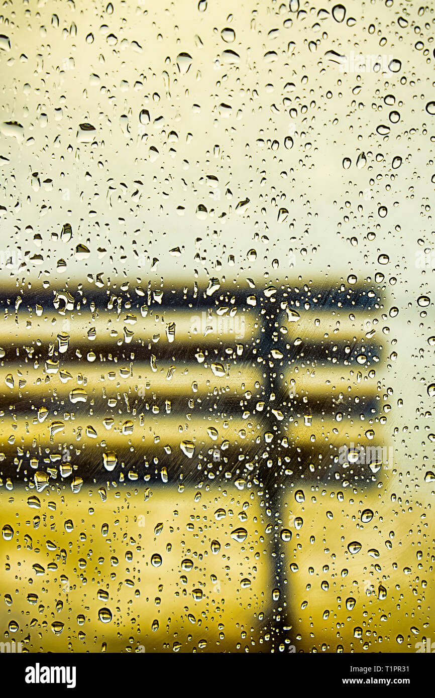 A metà strada fotografato da banco attraverso la finestra sotto la pioggia con gocce su di esso. Foto Stock