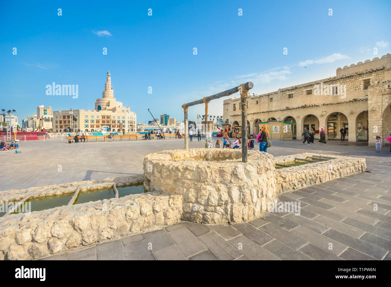 Doha, Qatar - 20 Febbraio 2019: vecchio pozzo fontana, famoso punto di riferimento al Souq Waqif e Fanar Centro Culturale Islamico con spirale Moschea e minareto su Foto Stock