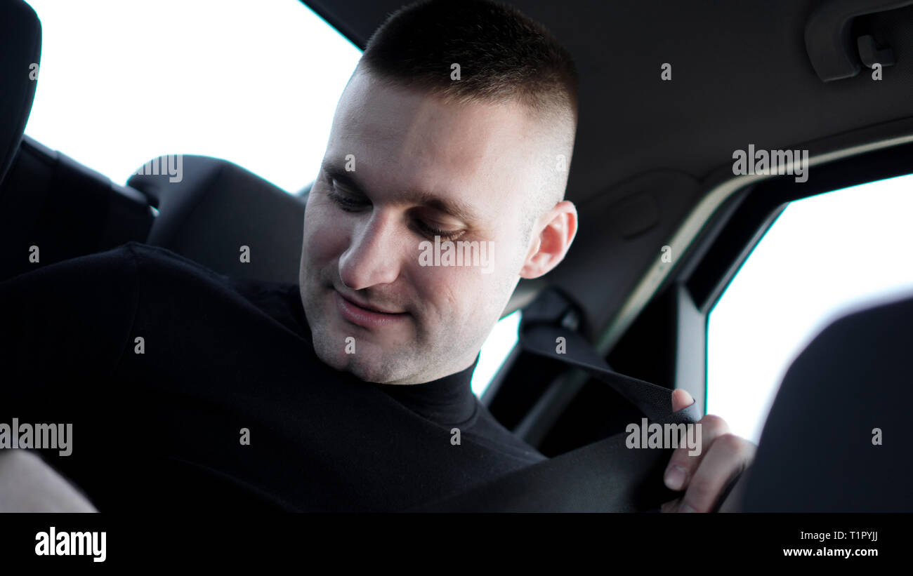 Fiducioso giovane imprenditore ed elegante nella sua auto il fissaggio della cintura di sicurezza, guida sicura di concetto Foto Stock