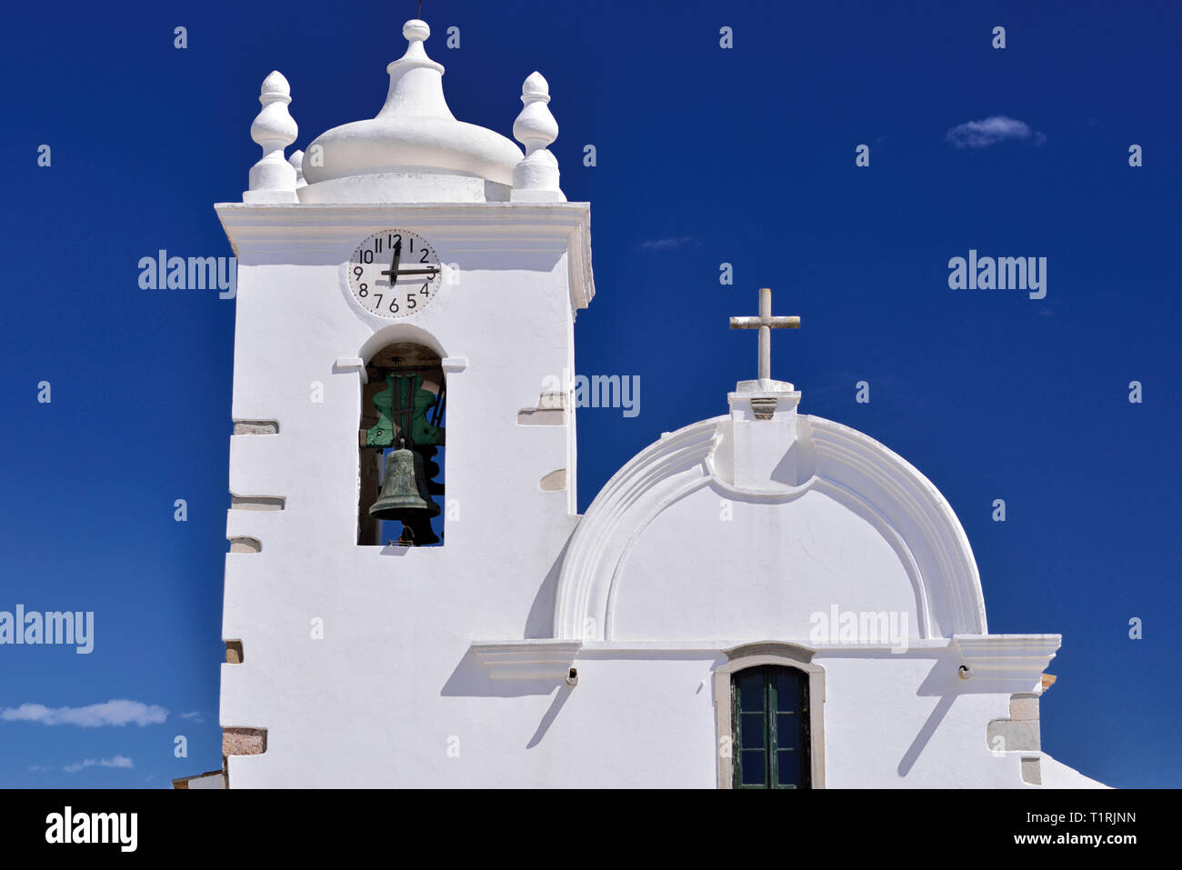 In alto di un bianco luminoso medievale chiesa con campanile in contrasto con il cielo blu in una giornata di sole Foto Stock