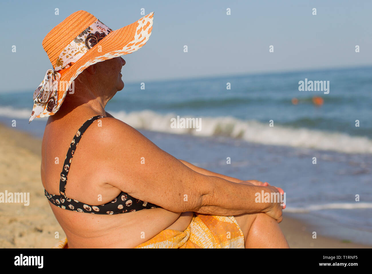 Nonna in vacanza. Donna anziana in un costume da mare. Il vecchio uomo seduto sulla spiaggia Foto Stock