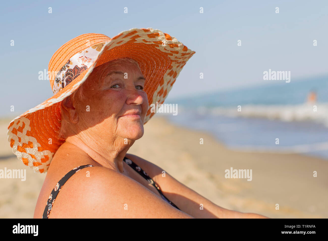 Nonna in vacanza. Donna anziana in un costume da mare. Il vecchio uomo seduto sulla spiaggia Foto Stock