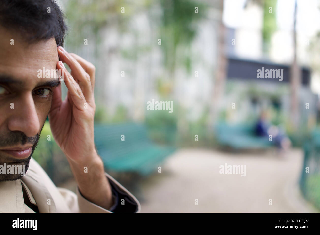 Uomo bello di il Pakistan, India, origine asiatica, seduta in city park, mano a testa Foto Stock