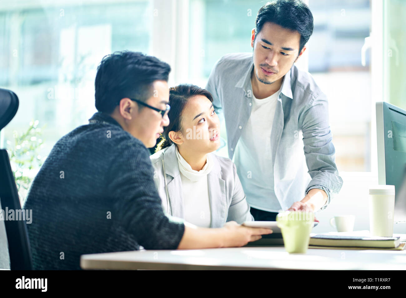 Tre giovani asiatici dirigenti aziendali che lavorano insieme a discutere di business plan in ufficio. Foto Stock