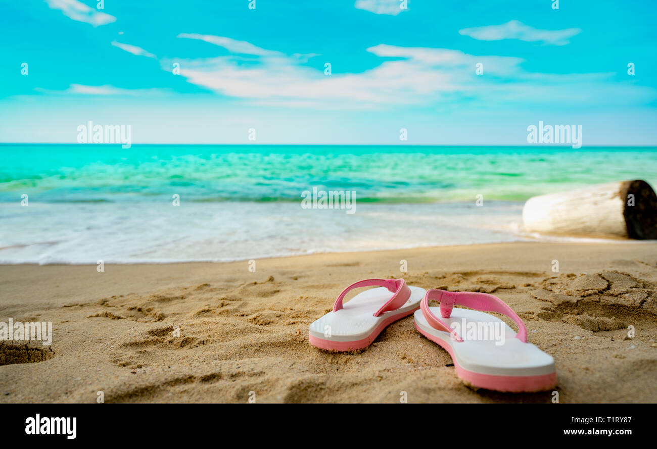 Rosa e Bianco sandali sulla spiaggia di sabbia. Stile Casual flip-flop sono stati rimossi in riva al mare a. La vacanza estiva sulla spiaggia tropicale. Vacanza divertente il viaggio sulla sabbia Foto Stock