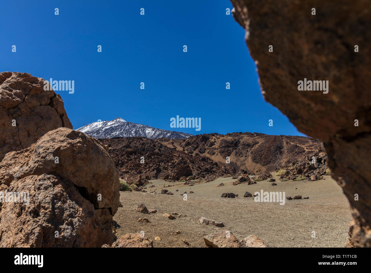 Coperte di neve vertice Teide visto al di sopra di un flusso di lava solidificato in Las Canadas del Teide national park, Tenerife, Isole Canarie, Spagna Foto Stock